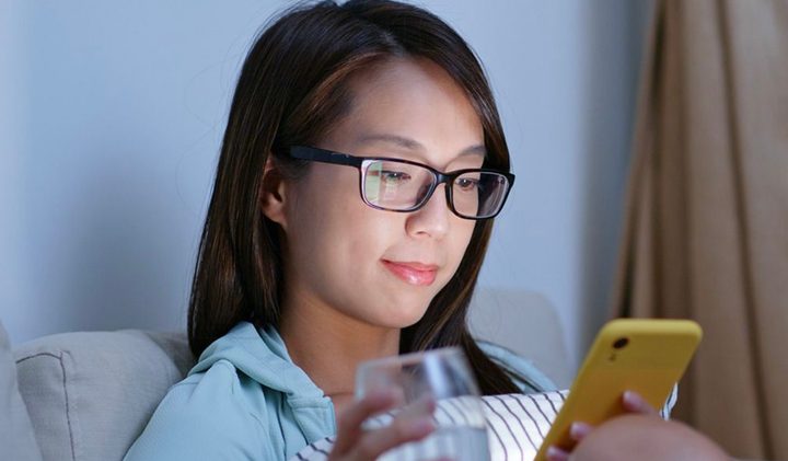 Woman wearing glasses while scrolling on her phone.