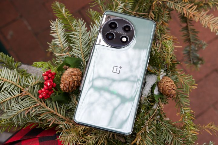 The OnePlus 11 lying face-down on a railing with Christmas decorations.