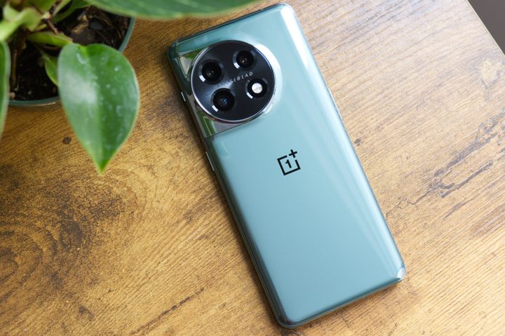 OnePlus 11 (in green) lying face-down on a desk.