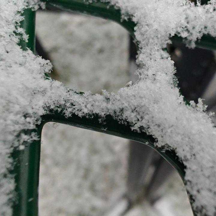 Macro photo of snow on a green picnic table.