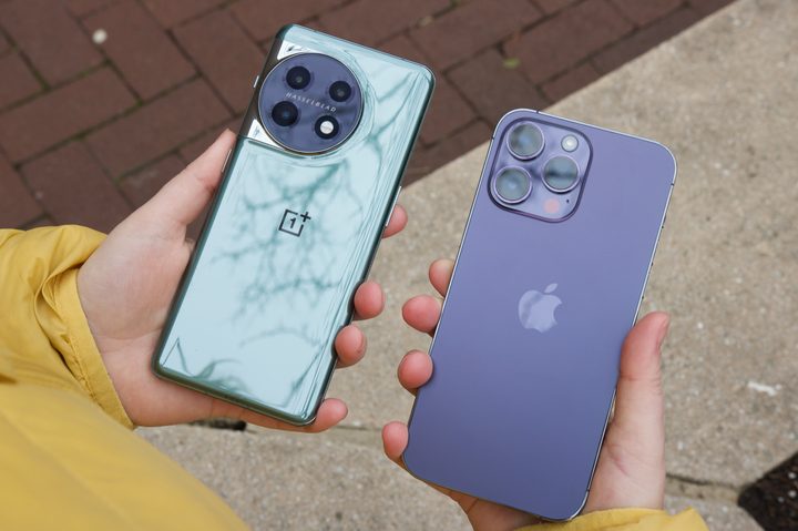 Someone holding the OnePlus 11 and iPhone 14 Pro side-by-side.