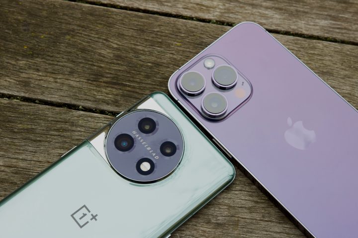 The OnePlus 11 and iPhone 14 Pro lying next to each other on a table.