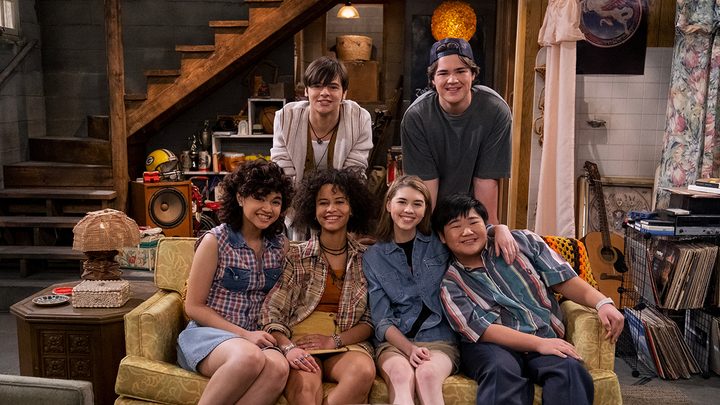 The cast of kids from That '90s Show posing around the basement couch.