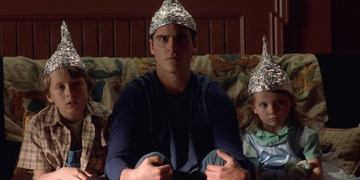 A family sits on the couch wearing tinfoil hats in Signs.