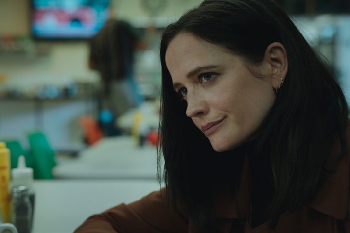 Eva Green sits at a restaurant table in Liaison.