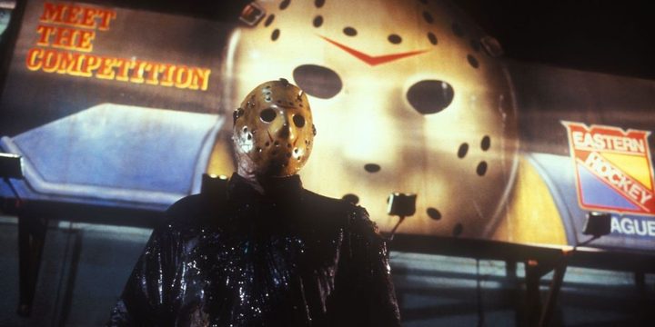 Jason Voorhees stands in front of a billboard of a hockey mask.