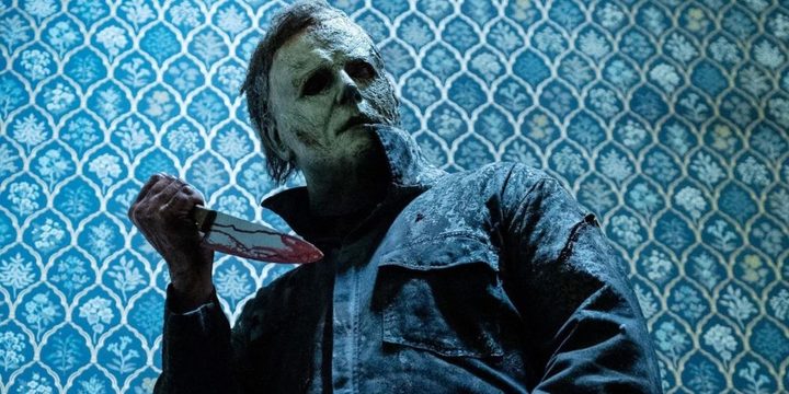 Michael Myers looks at one of his victims while holding a knife.