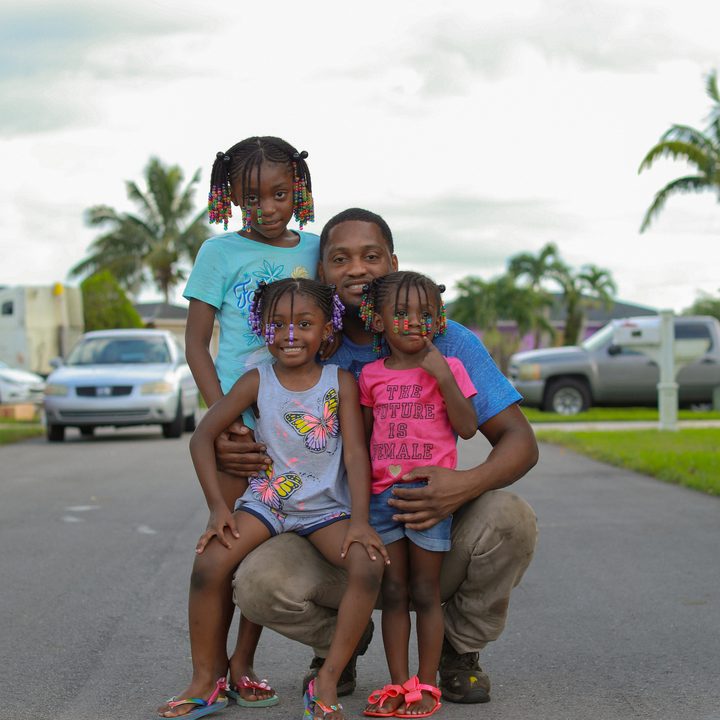 A man holds three children from Outta the Muck.