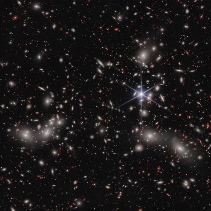 Bright white sources surrounded by a hazy glow are the galaxies of Pandora’s Cluster, a conglomeration of already-massive clusters of galaxies coming together to form a megacluster.