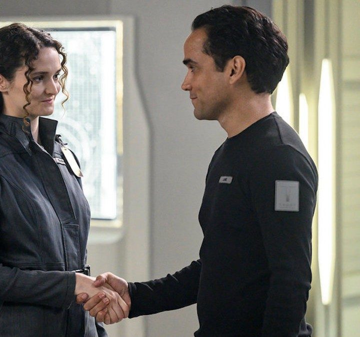 Two people shake hands in a scene from The Ark.