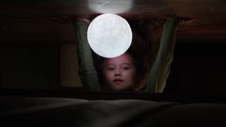 A girl puts her hand on the ground with a light in front of her face in The Boogeyman.