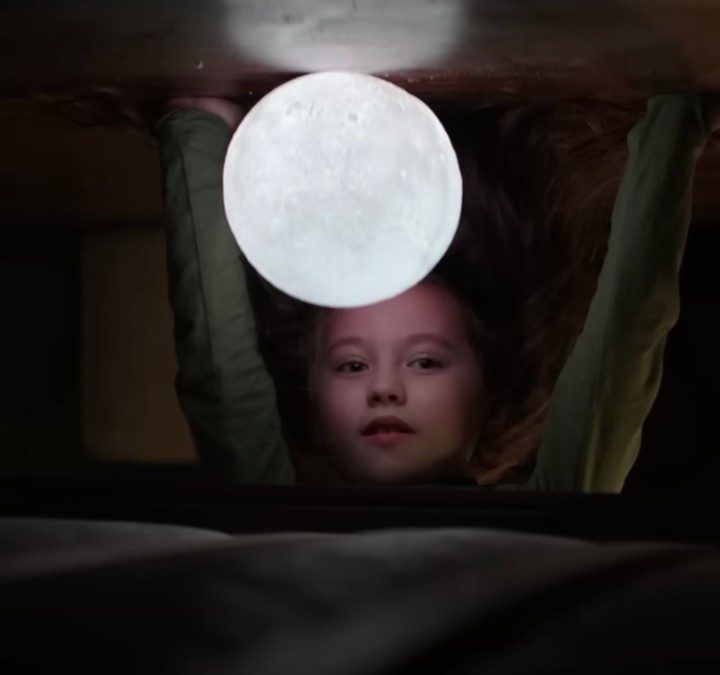 A girl puts her hand on the ground with a light in front of her face in The Boogeyman.