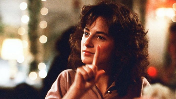 Marlee Matlin holding up a finger in a scene from Children of a Lesser God.
