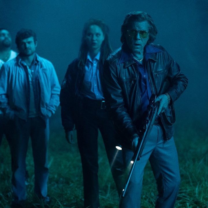 Ray Liotta holds a rifle in the dark alongside the cast of Cocaine Bear.