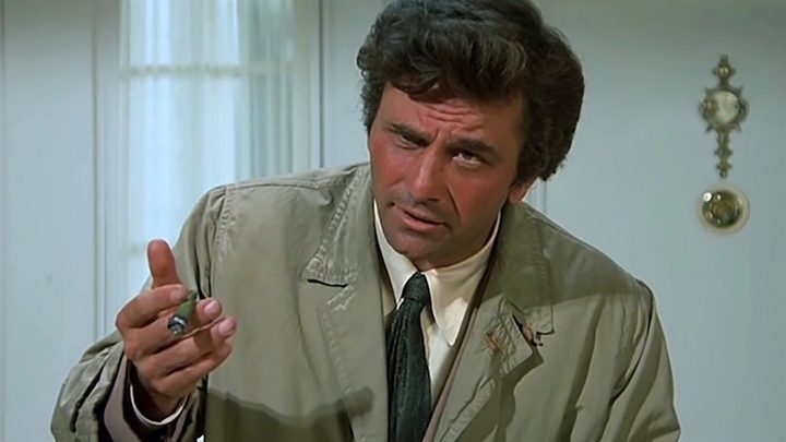 Columbo with one eye closed, hand in the air talking in a scene from the series.