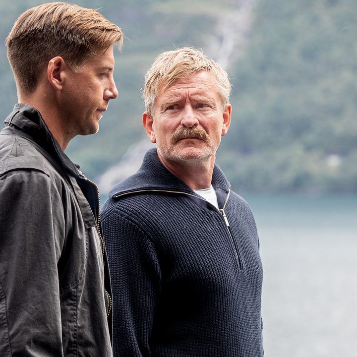 Two men converse in front of a lake in Furia.