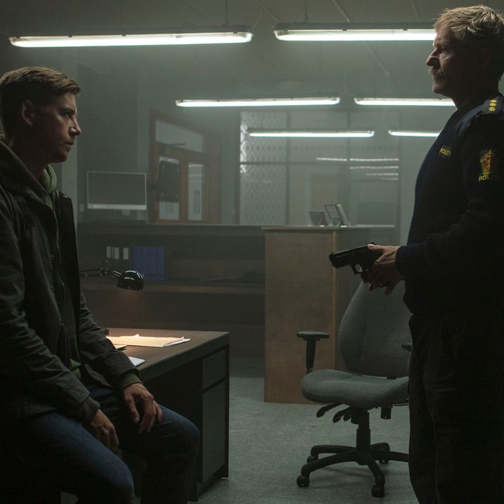 A man sits on a desk and talks to another man standing in Furia.