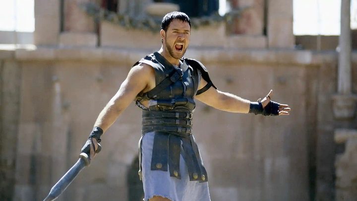 Russell Crowe standing and yelling in a scene from Gladiator.