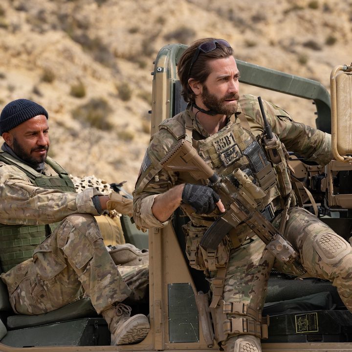 Jake Gyllenhaal sits on the side of a jeep in a scene from The Covenant.