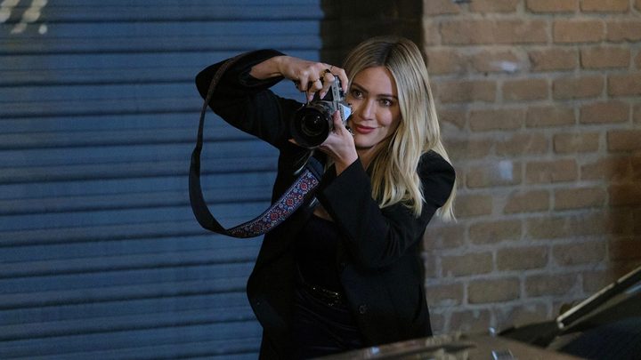 The younger Sophie holding up her camera to take a photo in a scene from How I Met Your Father.