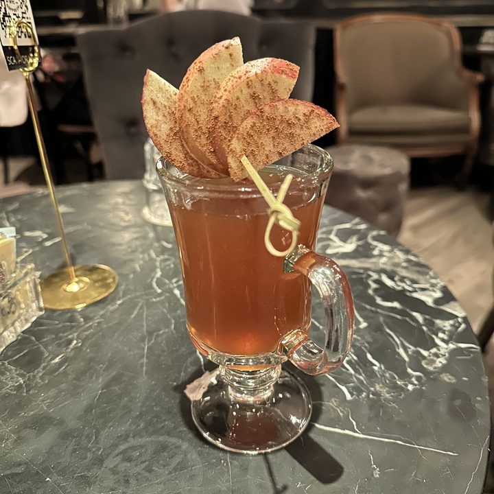 Night mode photo of a drink with apples on top of it.