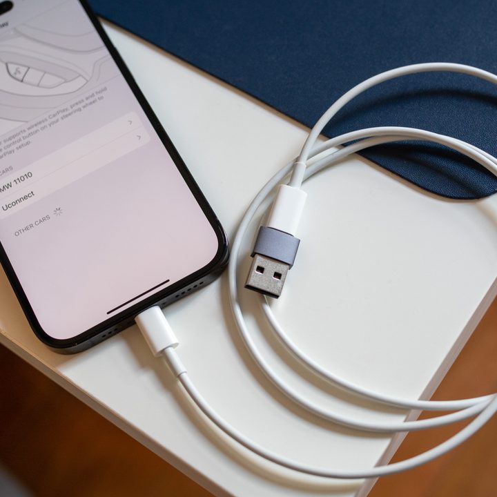An iPhone with USB-C cable and USB-A adapter.