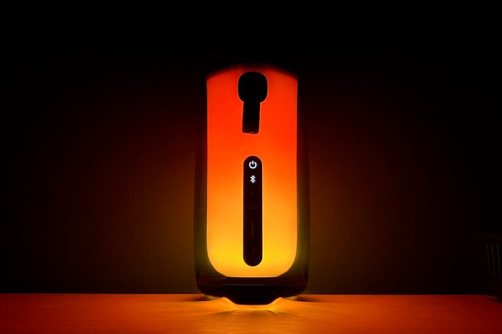 The JBL Pulse 5, glowing orange in the dark.