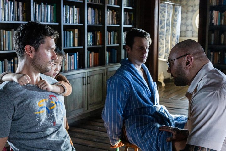 Bn Aldridge and Jonathan Groff are tied to chairs while Dave BAutista talks to them.