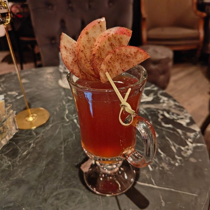 Night mode photo of a drink with apples on top of it.