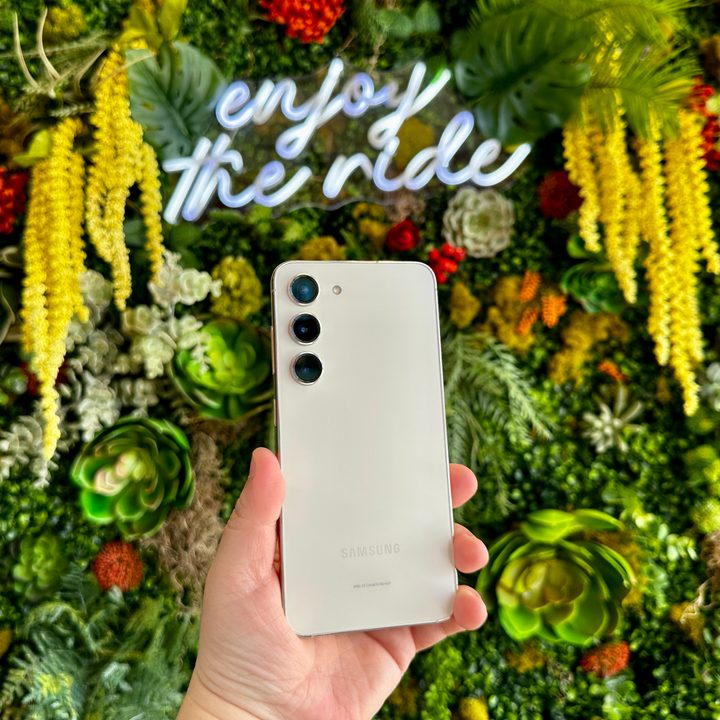 Samsung Galaxy S23 held in hand against green floral backdrop