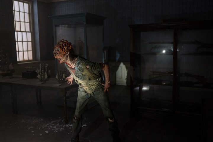 A clicker is in walking through a dark museum room. illuminated by a flashlight.