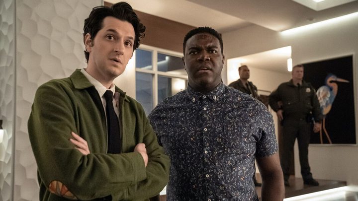 Two young man stand looking confused in a scene from The Afterparty on Apple TV+.