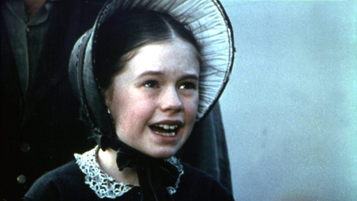 Anna Paquin in The Piano wearing a bonnet and smiling.