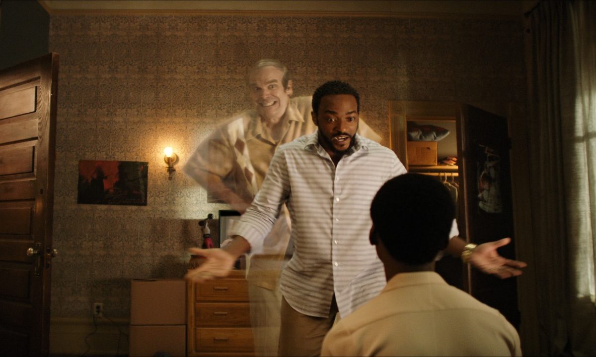 David Harbour, as a ghost, peeks out from behind Anthony Mackie in a scene from We Have A Ghost.