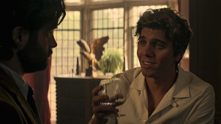 Adam from You talking to Joe, looking worried but also smiling and holding up a glass.