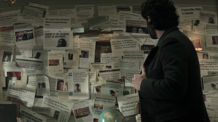 Joe from You looking at a collage of old newspaper articles on his wall in season 4.