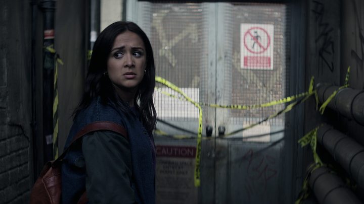 Nadia standing by a doorway looking terrified in a scene from You season 4.