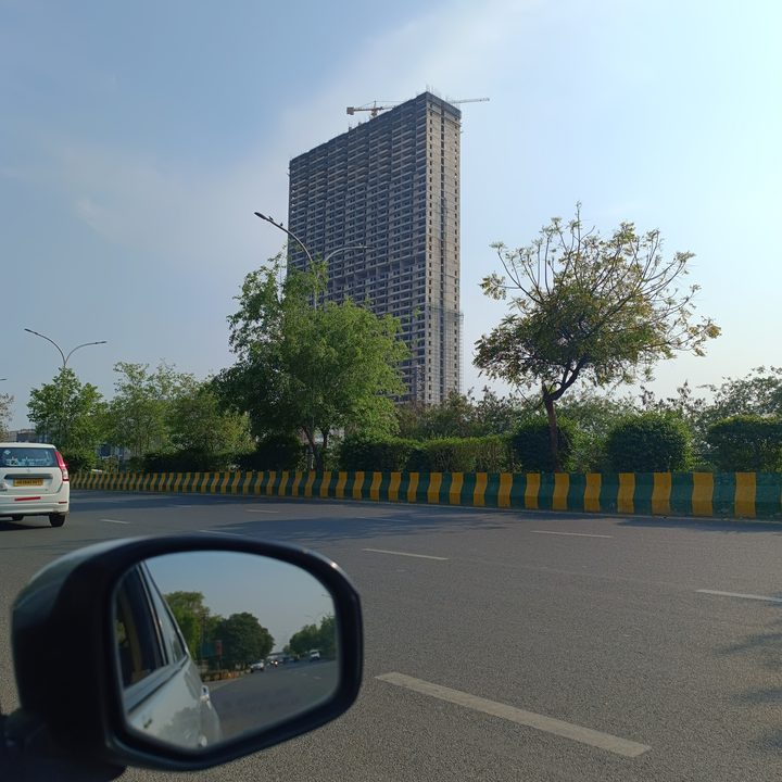 Multi-storey building under construction on the side of a road captured by Redmi Note 12 Pro Plus.