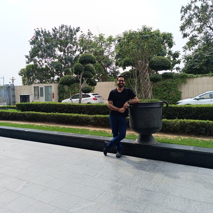 Man leaning againt a large vase in a hotel driveway captured by Redmi Note 12 Pro Plus.