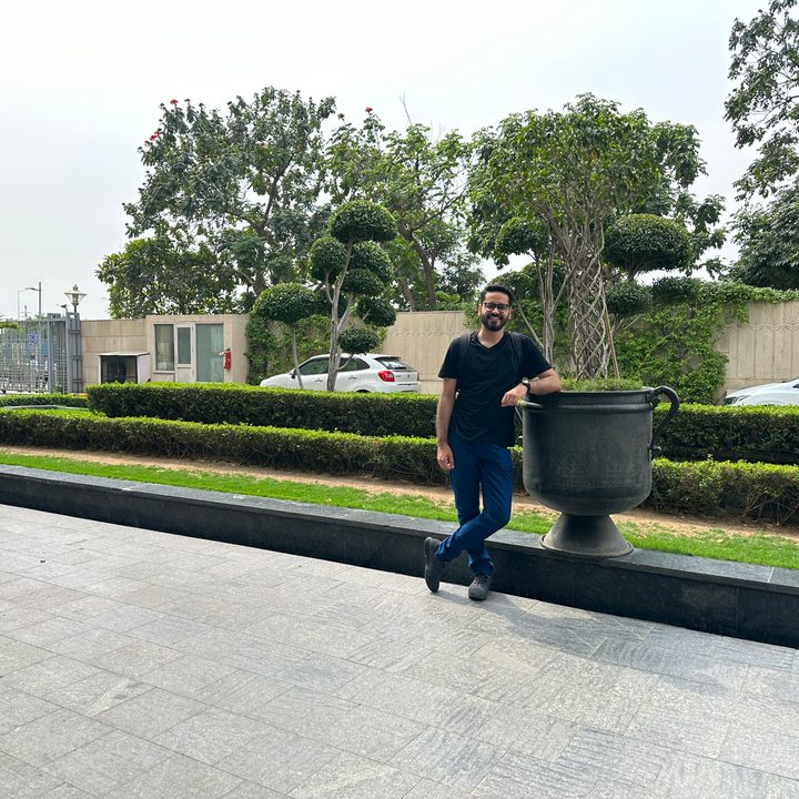 Man leaning againt a large vase in a hotel driveway captured by iPhone 14 Pro.
