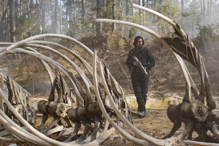 Adam Driver stands near a dinosaur skeleton in 65.