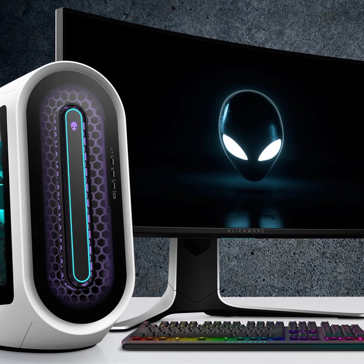 The Alienware Aurora R13 gaming desktop on a desk next to a monitor.