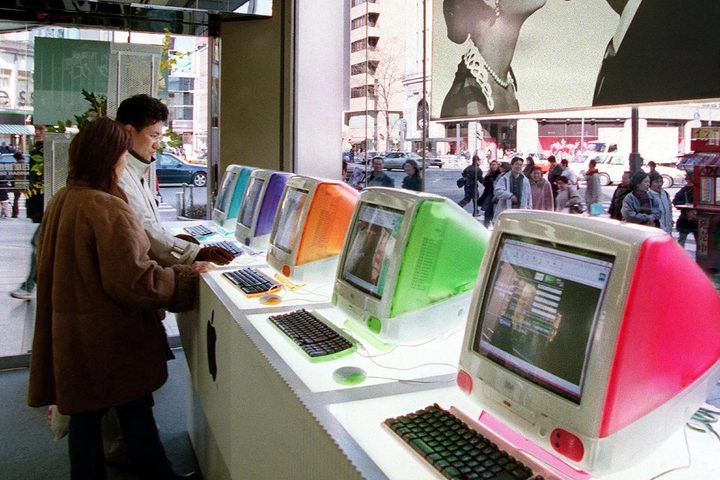 Customers look at a row of brightly coloured iMac G3 computers in an Apple Store.