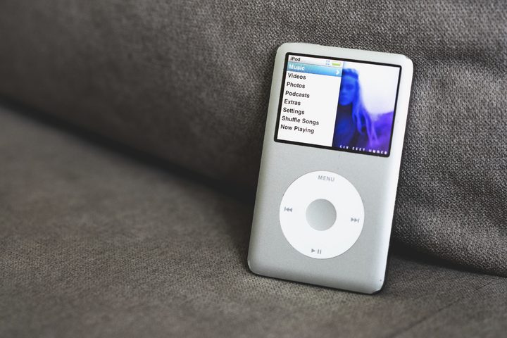 An Apple iPod resting on a couch seat.