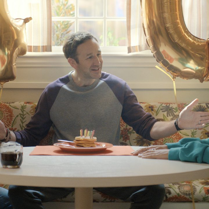 A family sit around a table in The Big Door Prize.