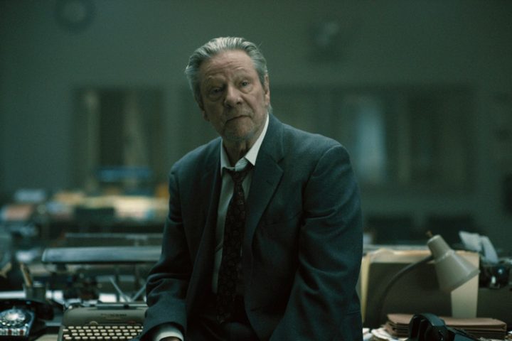 Chris Cooper sits on a news desk in Boston Strangler.
