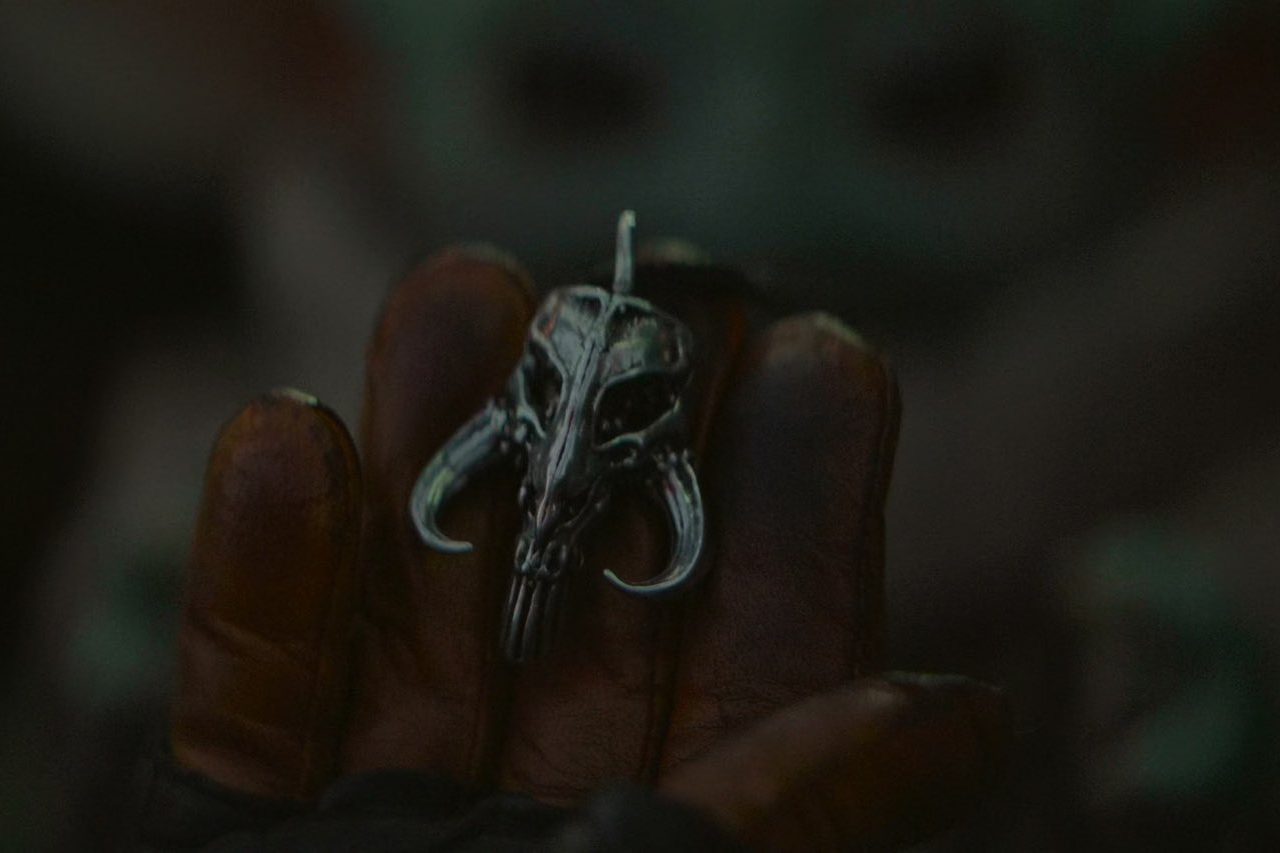 Din Djarin holds a mythosaur pendant in The Mandalorian.