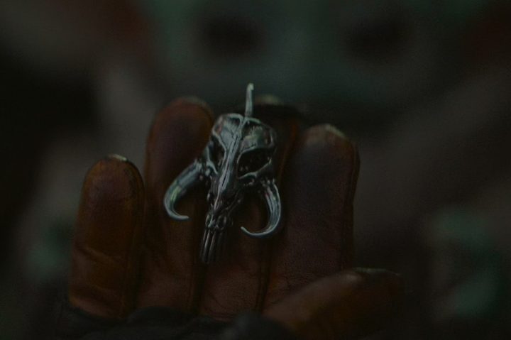 Din Djarin holds a mythosaur pendant in The Mandalorian.