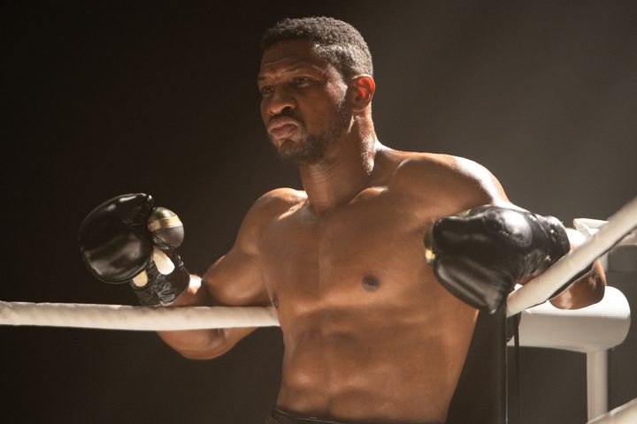 Jonathan Majors stands in a boxing ring corner in Creed 3.