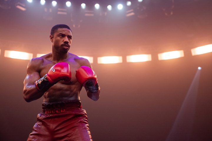 Michael B. Jordan wears red boxing gloves and trunks in Creed 3.
